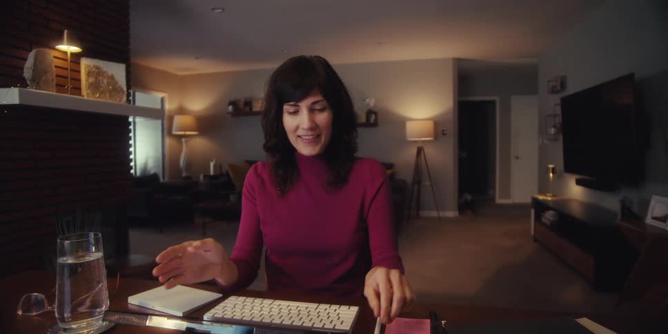 A woman in a living room talking to someone on a computer