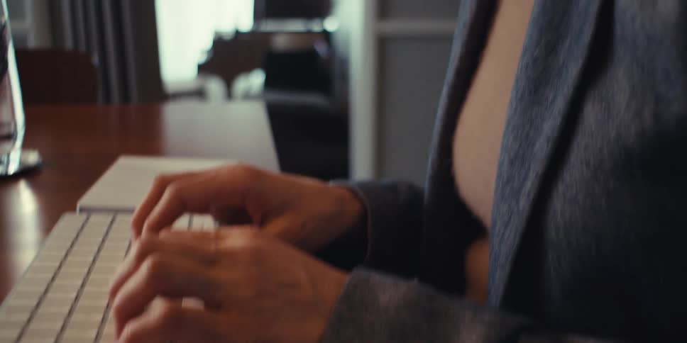 A woman smiles while typing on her keyboard