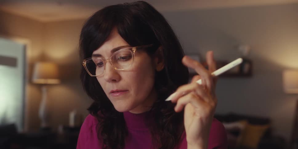 Woman in a room of the house with a thoughtful expression holding a pen