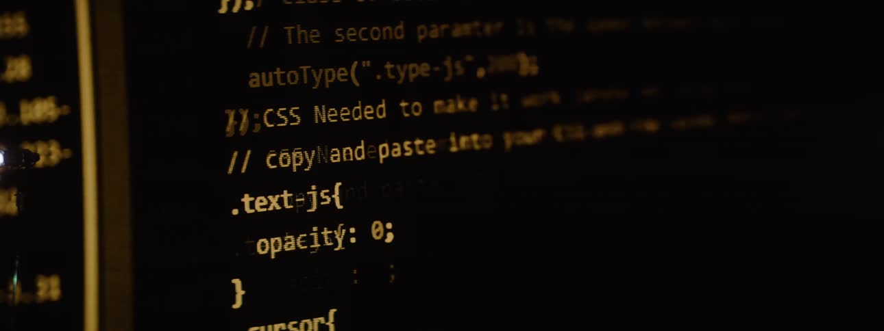 Lines of glowing yellow computer code rapidly scroll up a dark screen in a continuous flickering stream