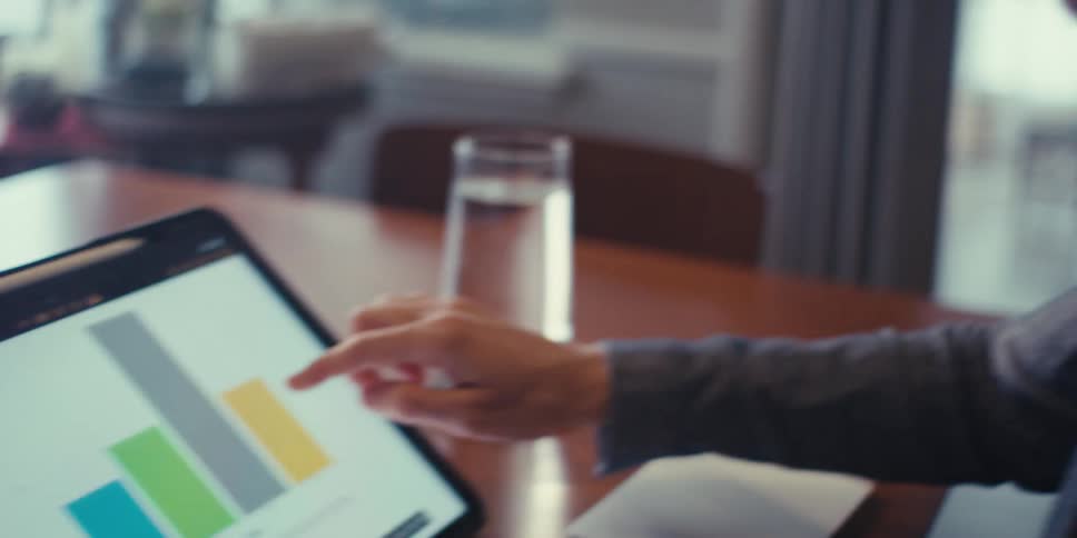 A woman scrolling graphs on a tablet
