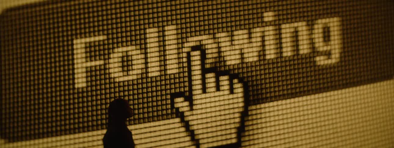 Silhouette of a woman next to a large screen displaying a moving mouse