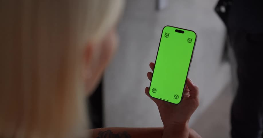 A woman holds a phone with a green screen ready for editing
