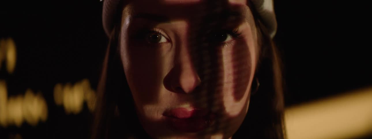 A persons face with shifting light and shadow patterns from a projection as their eyes open and look forward