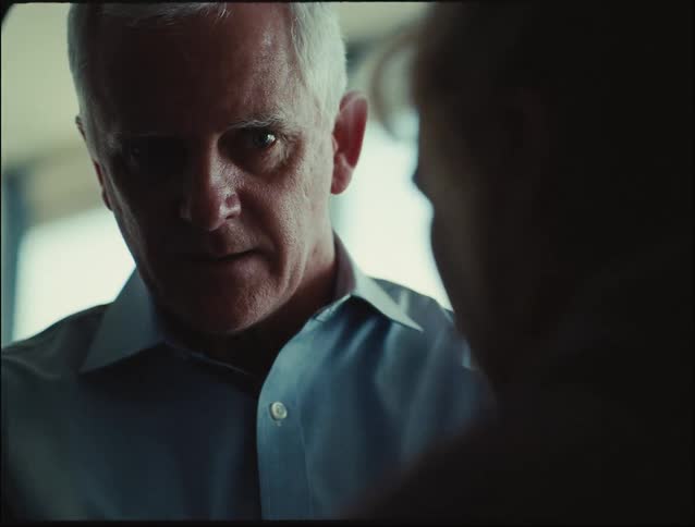 Grayhaired man talking to another person