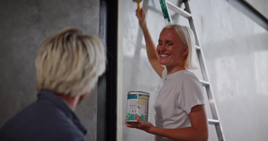 A footage of a lady painting while having a conversation with a man
