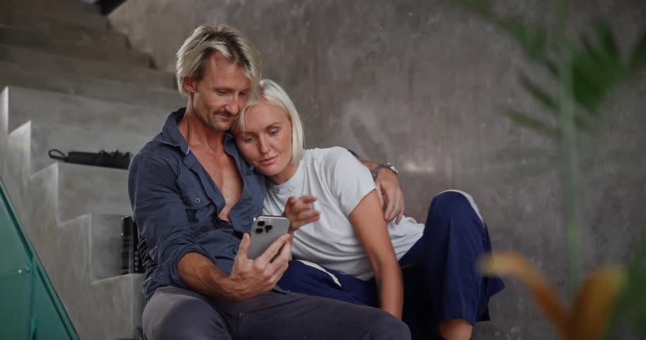 Couple sitting on stairs interacting with a smartphone
