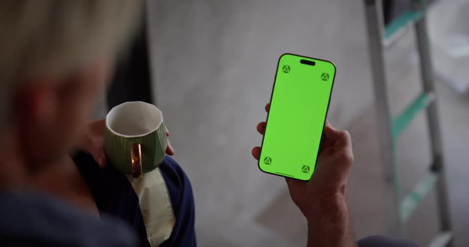 A man is checking his cell phone with a drink