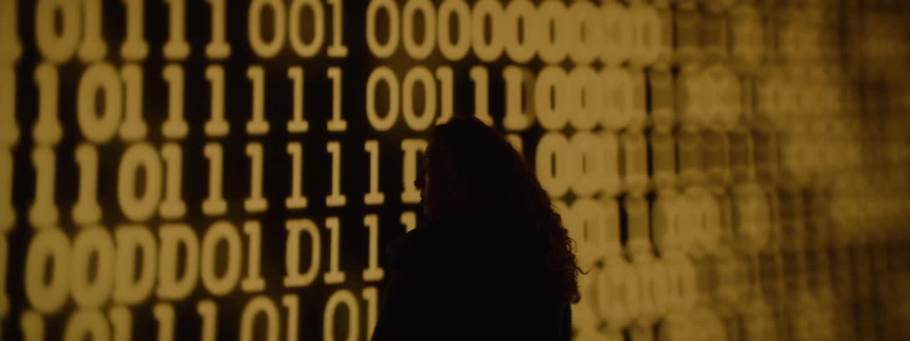 Silhouette of a woman facing a screen displaying numbers