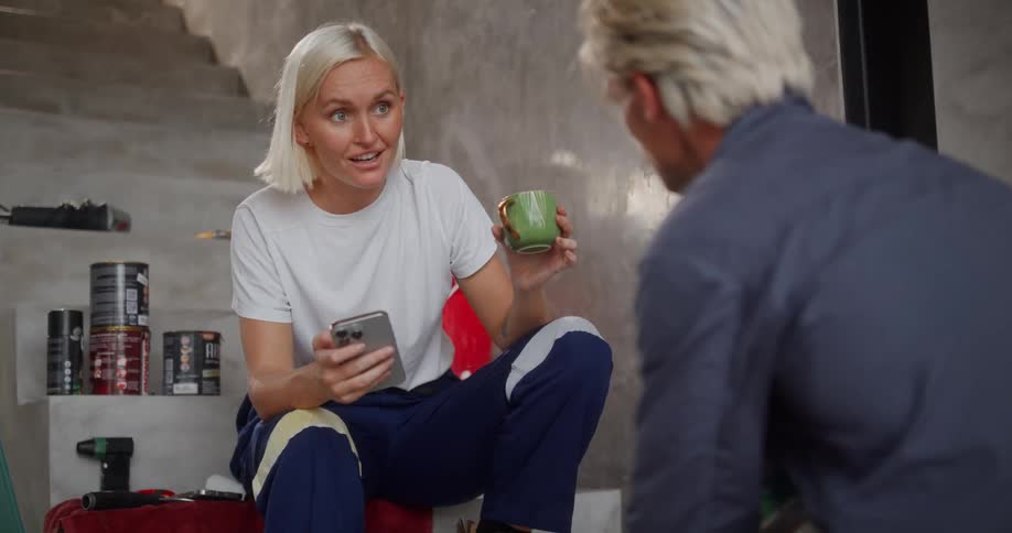 A woman is using a cell phone while she talks with a man