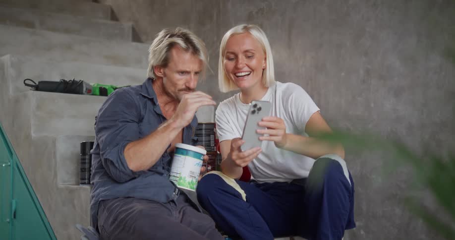 Man and woman sitting on a staircase and interacting with a smartphone