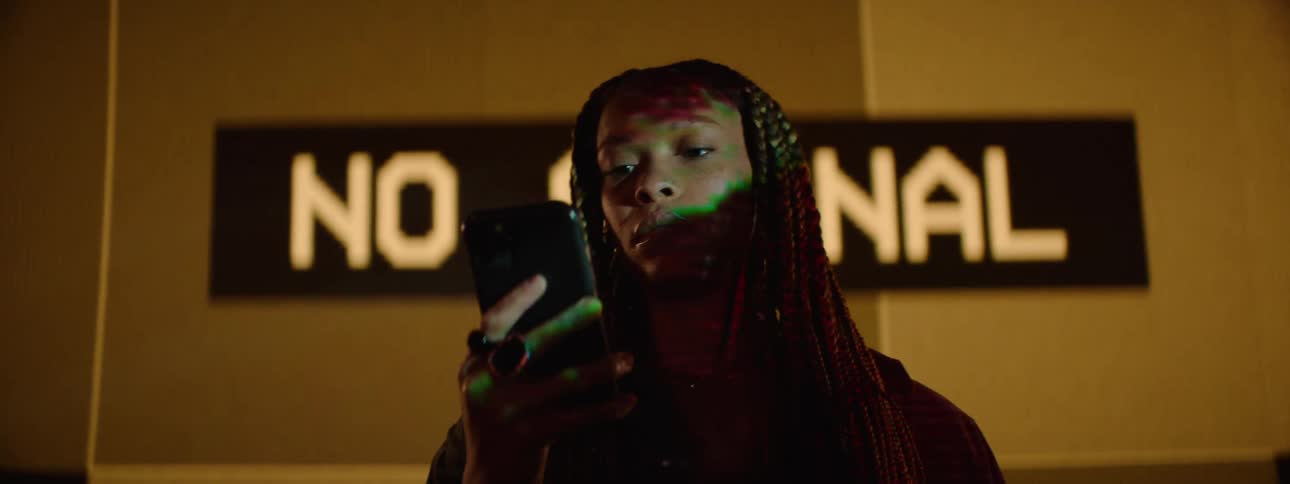 A woman stands in front of a large digital sign while looking at her phone
