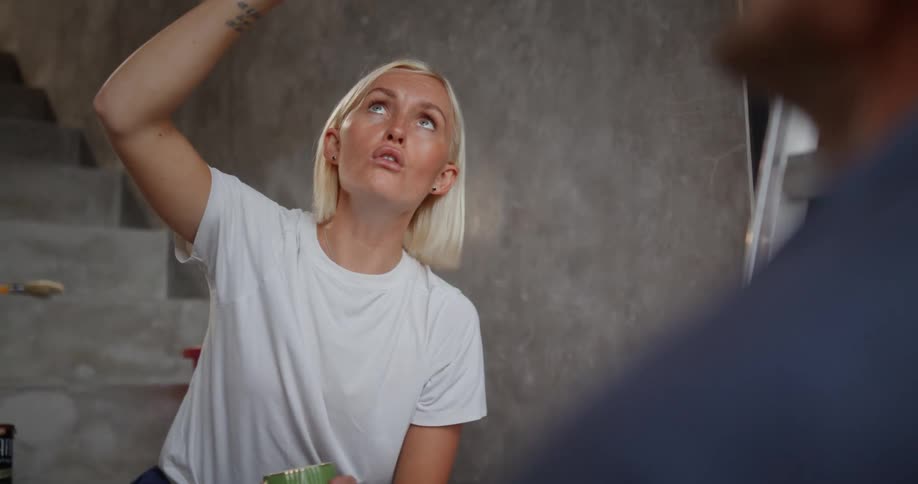 A woman waves her hand while talking with a man