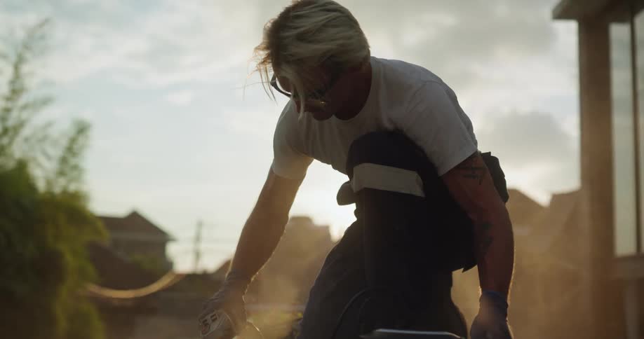 Man creates dust while sanding a surface outside a house on a cloudy day