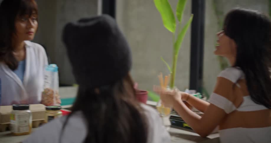Mother and her daughters converse while sitting at home in the kitchen during the daytime