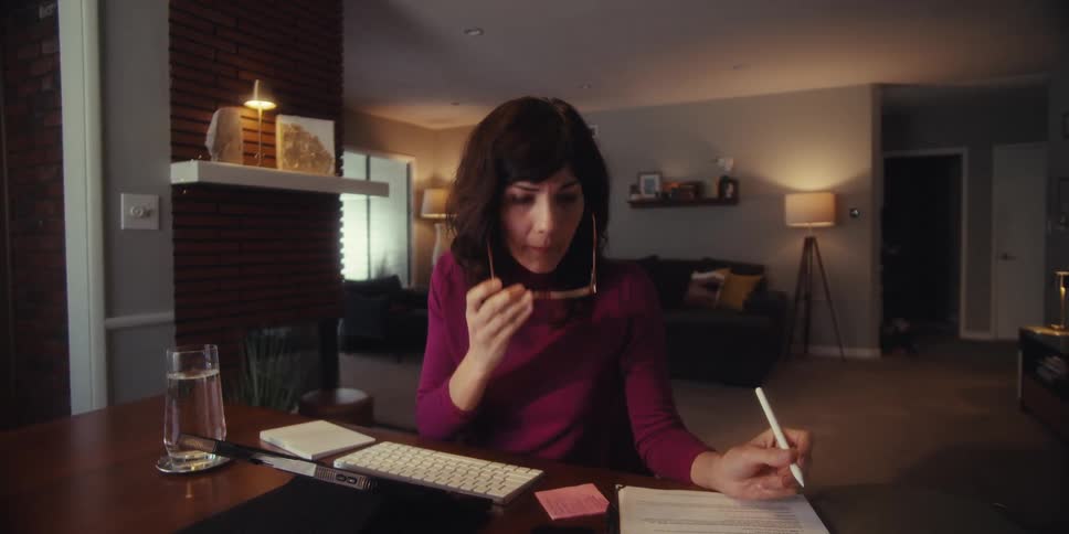 A woman is taking notes while talking on her tablet