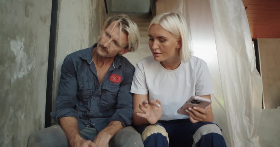 A man rubs the wall while talking with a woman