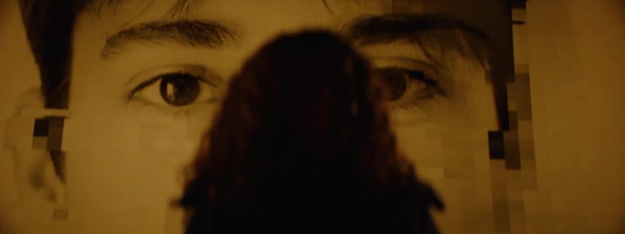 Portrait of a woman with curly hair and in the background a screen displaying abstract faces