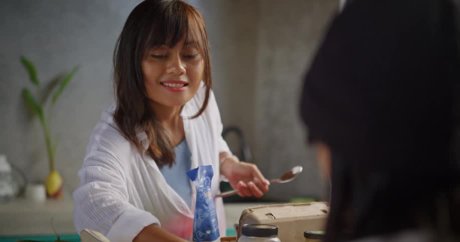 A girl studies while her mother cooks