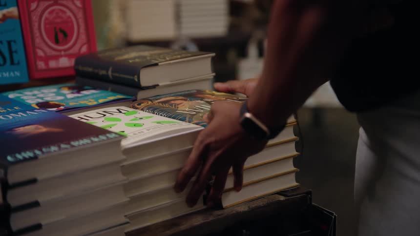 Stack of books being placed on a table in a bookstore
