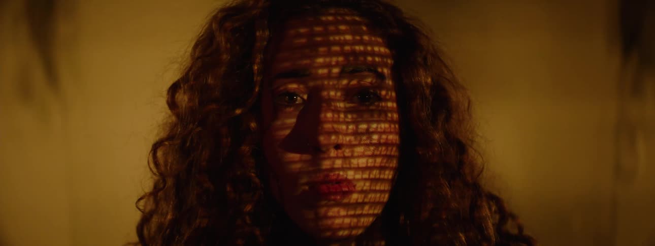 Portrait of a woman with a play of lights on her face and a screen in the background