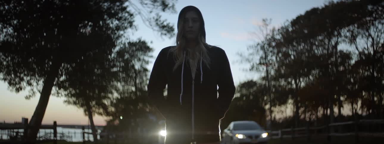 A woman stands on the road near some cars