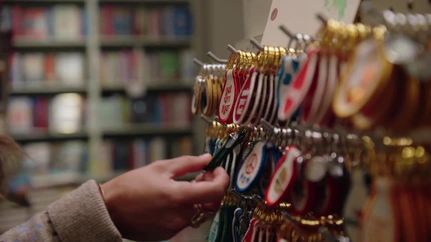 A woman browses through a display of colorful keychains in a store