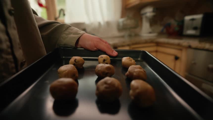 Pair of hands making dumplings placing them in a pan and putting them in the oven