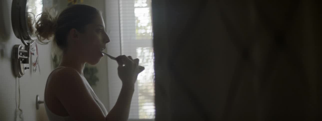 A woman is brushing her teeth in the bathroom