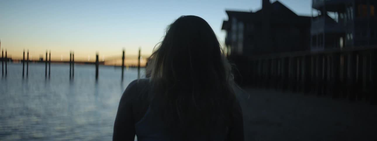 A woman walks on the seashore at dusk