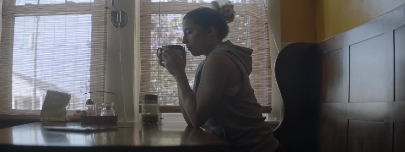 A woman sips from a hot cup at a table
