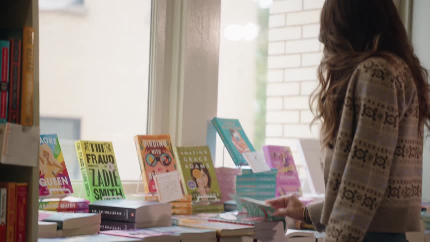 Customer browsing paperback books on a table at a bookstore