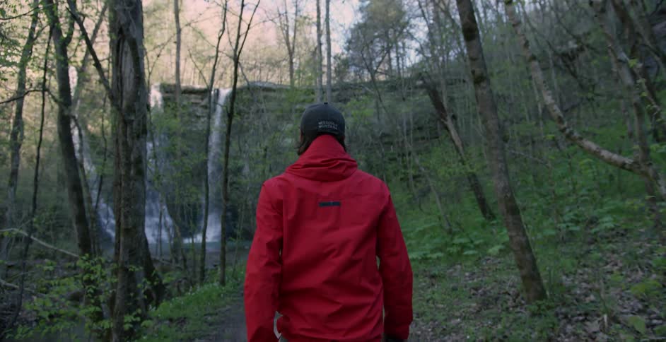 A man approaches a waterfall cascading over a cliff