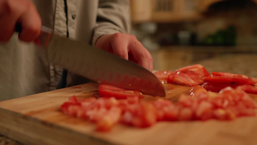 Hand with a knife chopping tomatoes