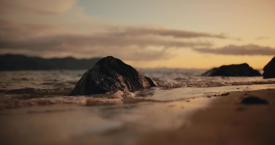 Waves hitting rocks on the beach at sunset