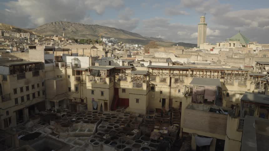 Traditional tannery in fez morocco with dye pits and old buildings under a partly cloudy sky