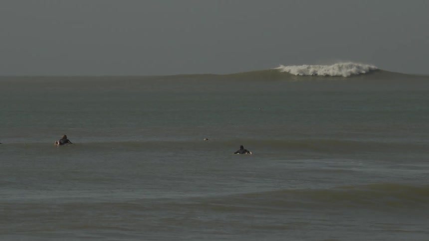 Surfers in a calm ocean with light waves
