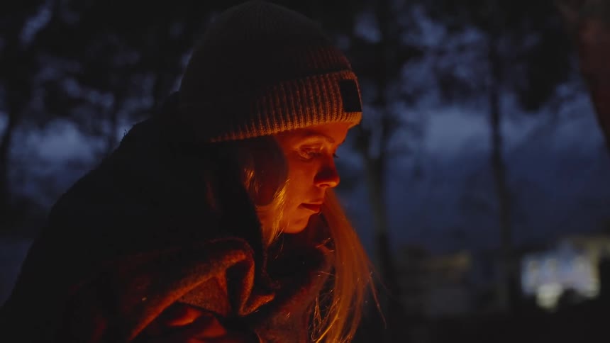A woman warms herself by the fire