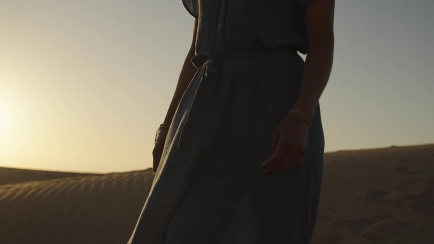 Woman wearing a dress walks through the desert alone