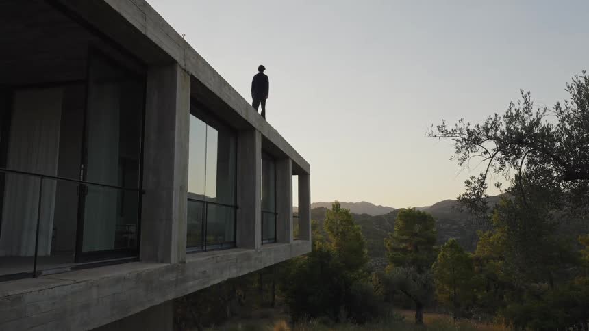 Person walking on the cliff of a house surface in nature