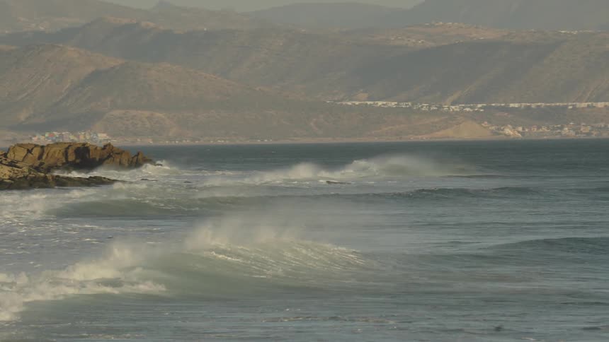 Small coastal community among mountains along the coast as waves roll in to shore