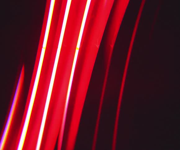 Intense beams of red light cross diagonally across a dark background