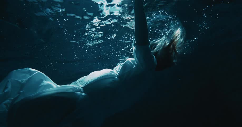 Woman wearing a white dress sinks underwater