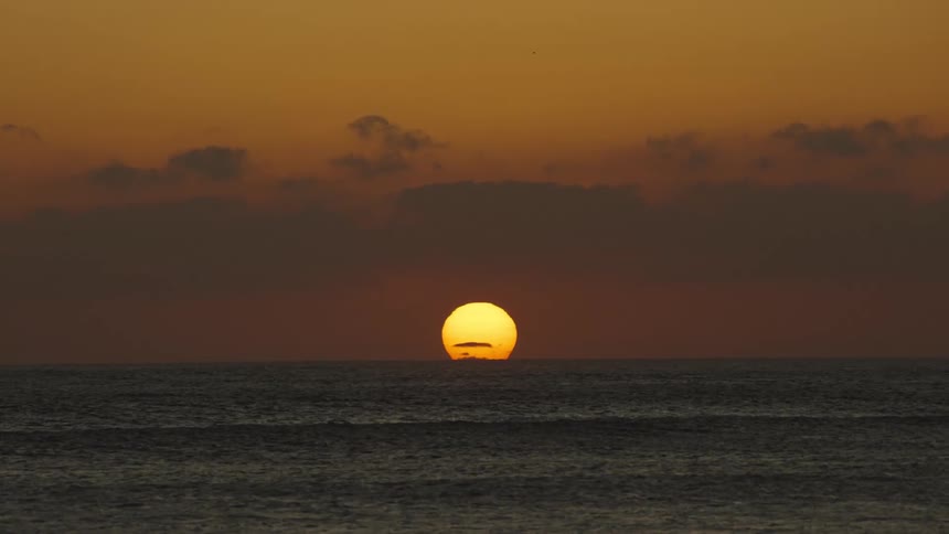 Big yellow sun setting on the horizon over the ocean