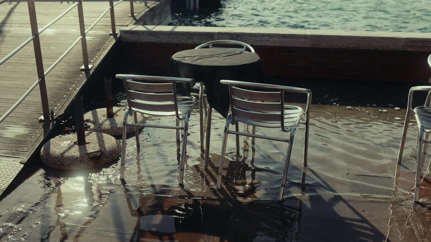 The chairs and tables are flooded by the shore