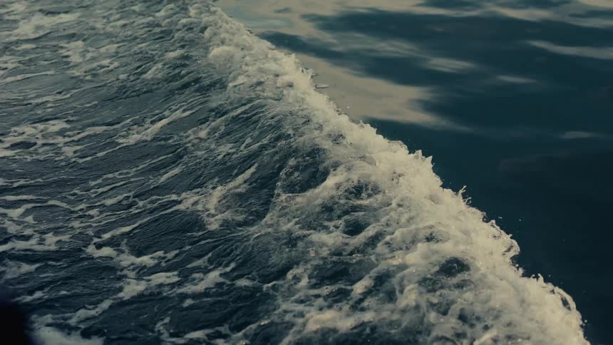 Watercraft creates a large wake while traveling across the water during the daytime
