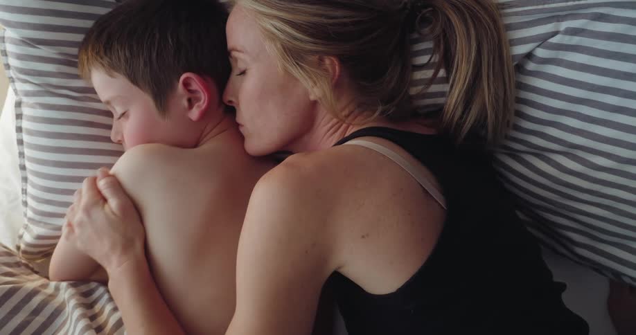 A woman embraces a child while sleeping in bed