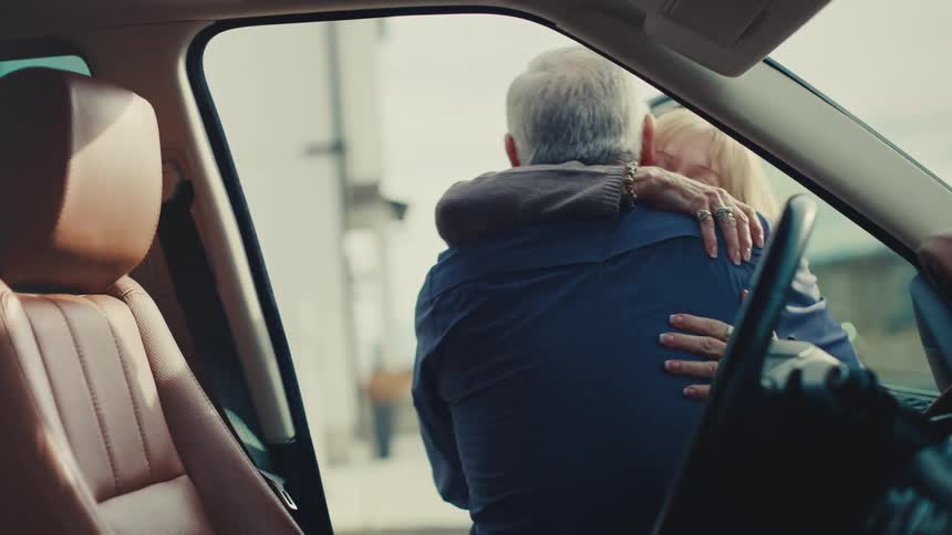 Woman hugs a man getting out of a car at daytime