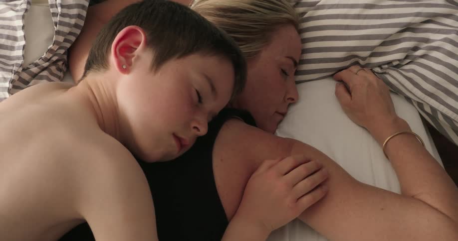 A young boy and a woman sleep peacefully sharing a quiet intimate moment