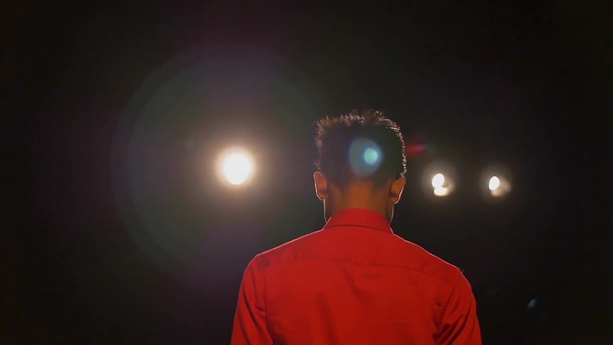 A boy walks with lights shining overhead